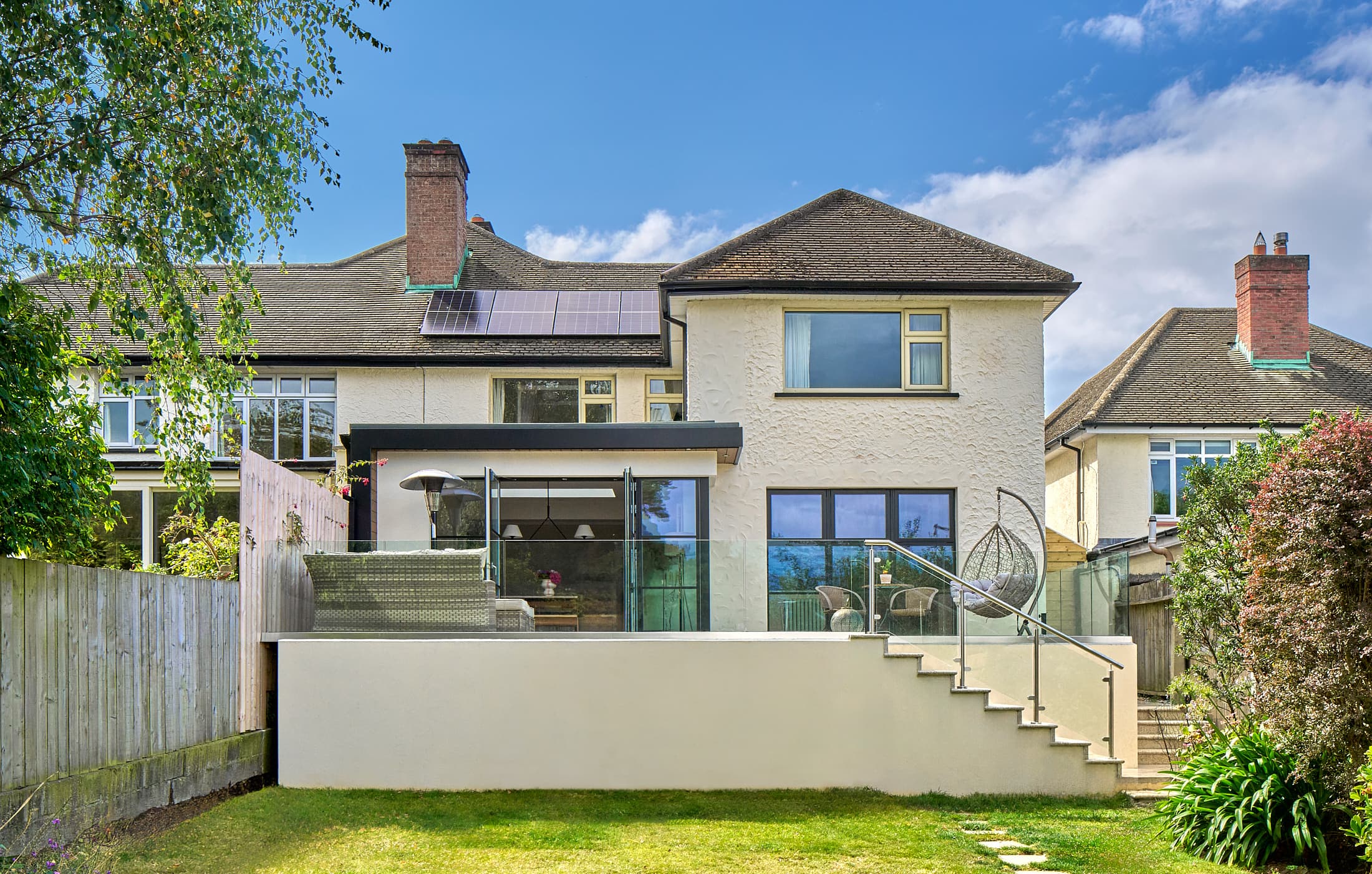 A single-storey rear extension by Shomera with black-framed glazing and a raised terrace, in Mount Merrion, Dublin